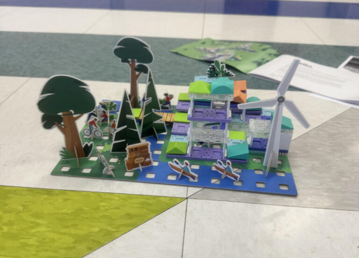 A child-made display of a house and yard landscape sitting on the ground.