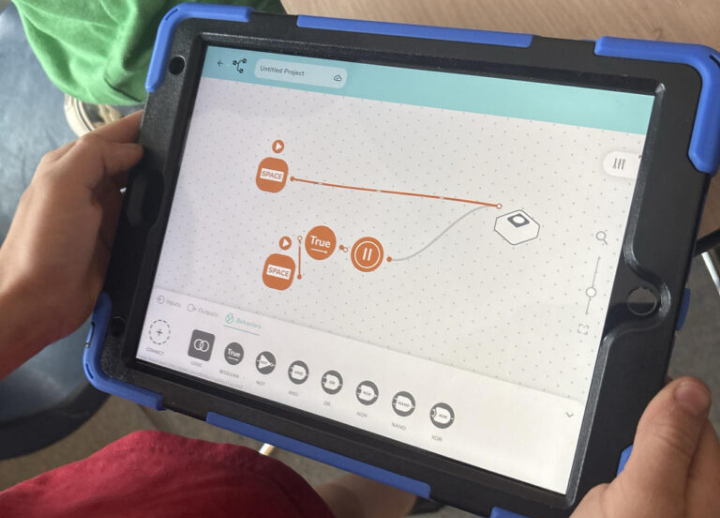 A child holds an ipad while working on an early coding program.
