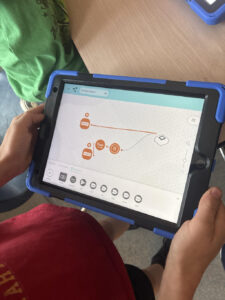 A child holds an ipad while working on an early coding program.