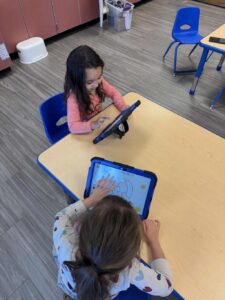 Children at table with tablets.