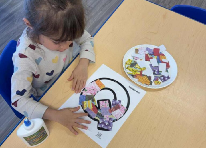 Child making paper craft for the letter Q.